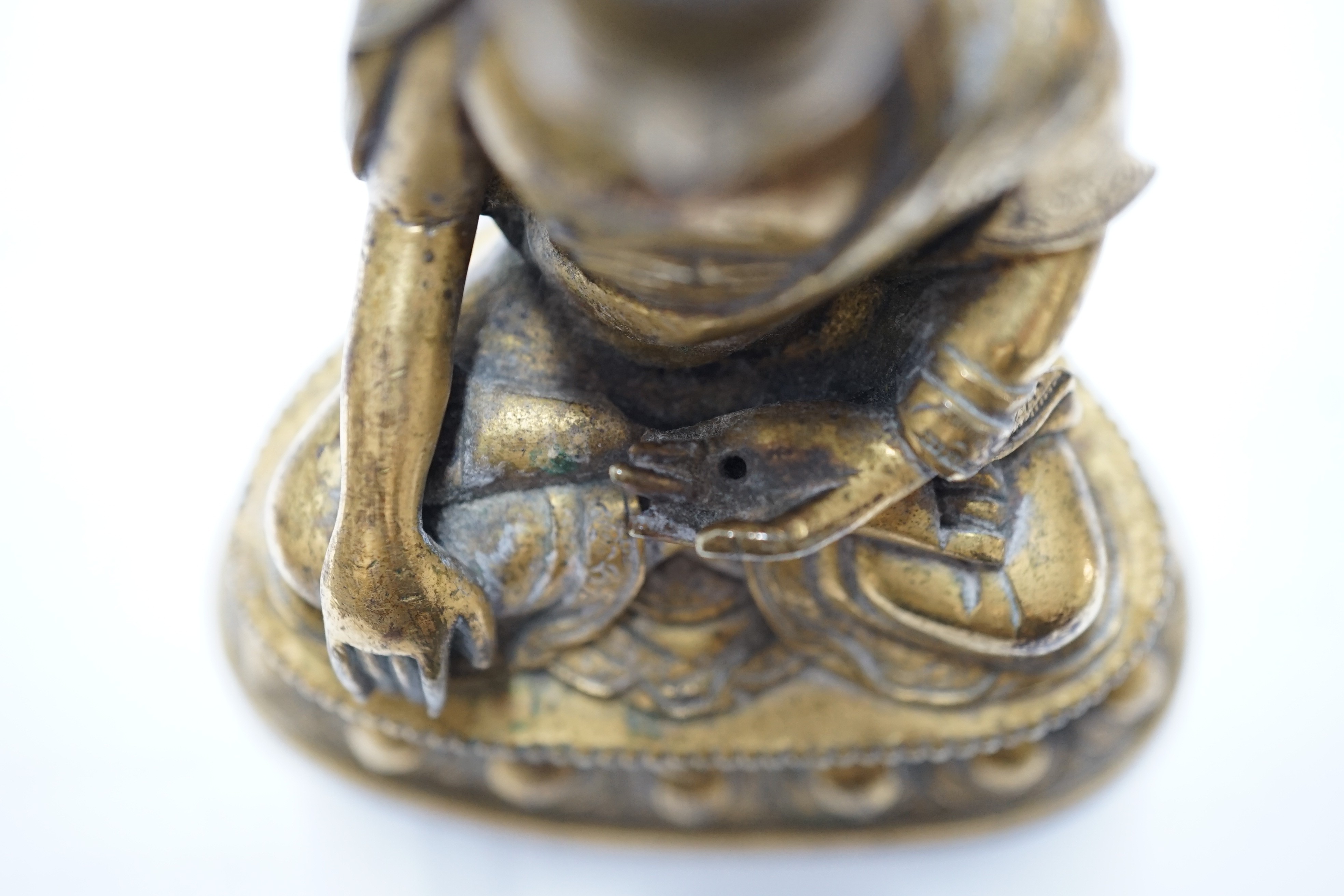 A small Tibetan gilt bronze seated figure of Buddha Shakyamuni, 18th century, 9.5cm high, lacking bowl in left hand